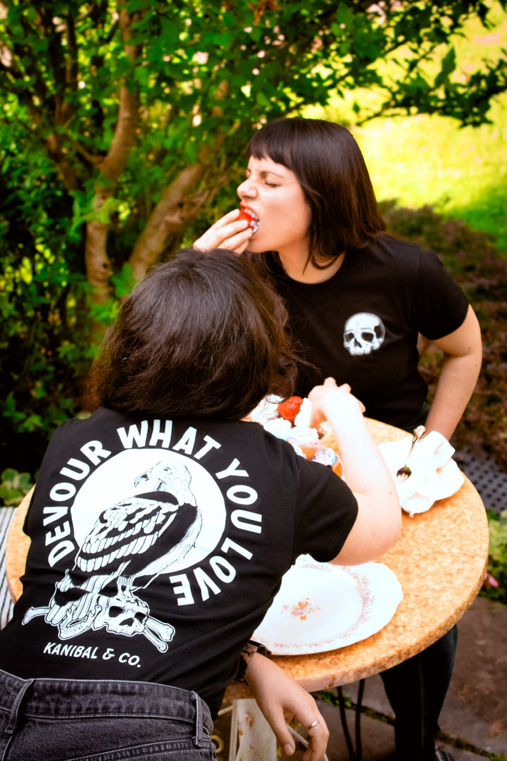 Kanibal & Co. devour what you love shirt with skull design worn by two women eating outdoors