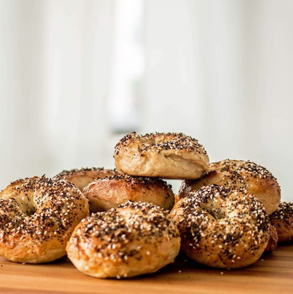 Freshly baked bagels stacked on wooden surface showcasing the DIY bagel and cream cheese kit
