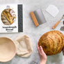 DIY sourdough bread kit with baking tools and freshly baked bread held in hands on marble surface