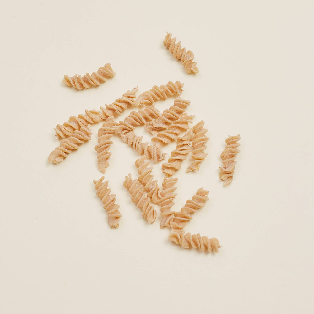Dried fusilli pasta on a beige background