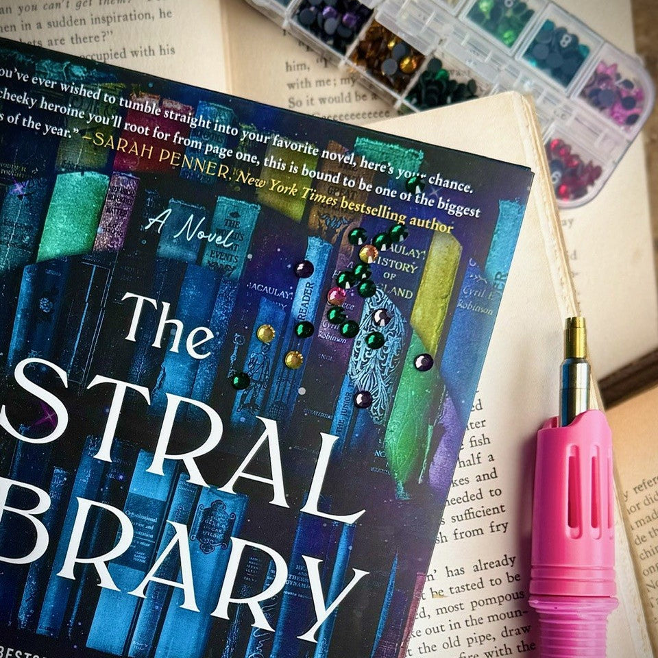 Book titled 'Thestral Library' with colorful bookmarks and a pink pen on a book background