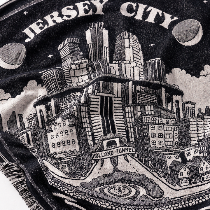 Embroidered design of Jersey City with buildings and 'Holland Tunnel' text on a black background.