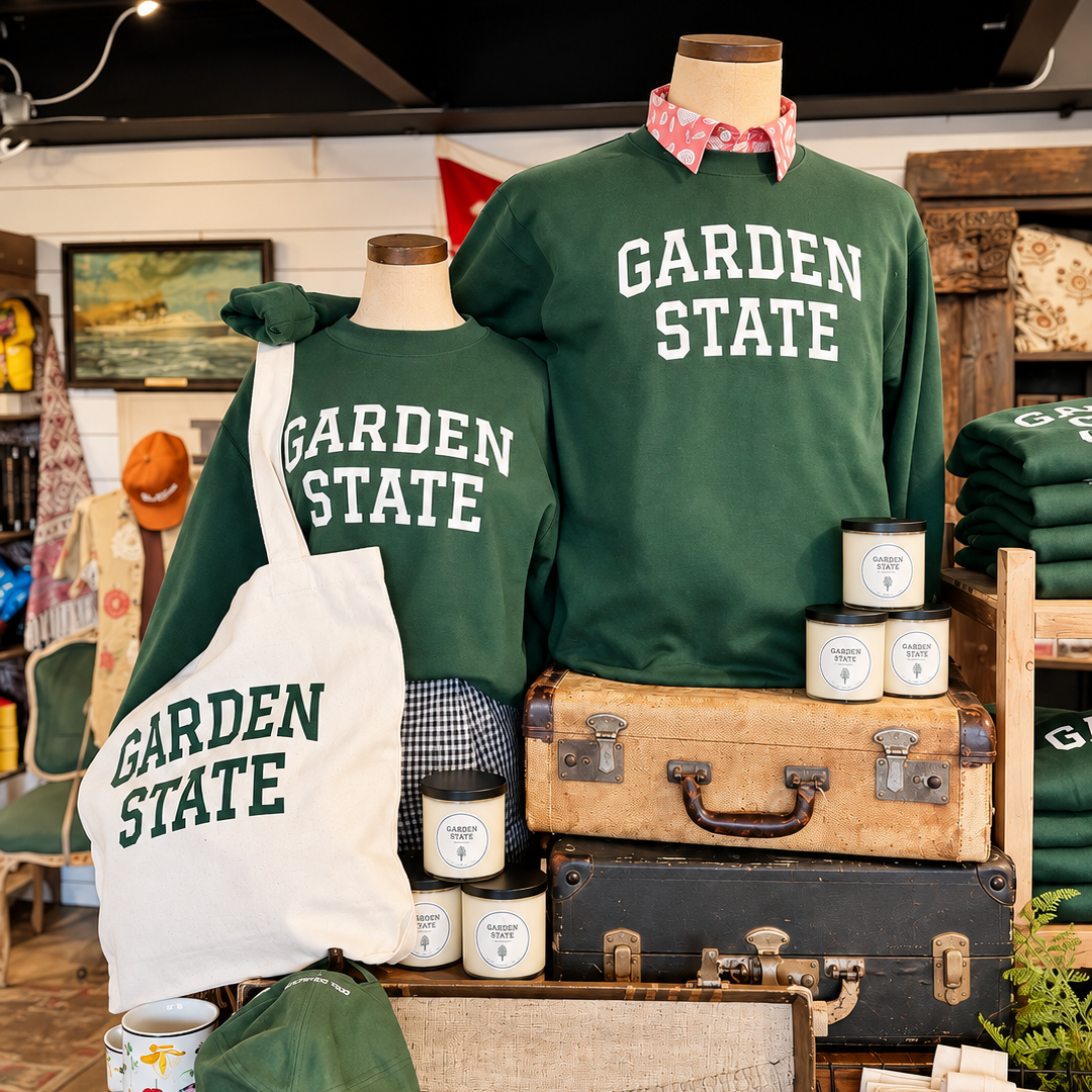 A retail display featuring two dark green crewneck sweatshirts and a matching tote bag printed with &