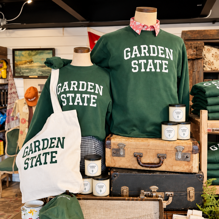 A retail display featuring two dark green crewneck sweatshirts and a matching tote bag printed with &