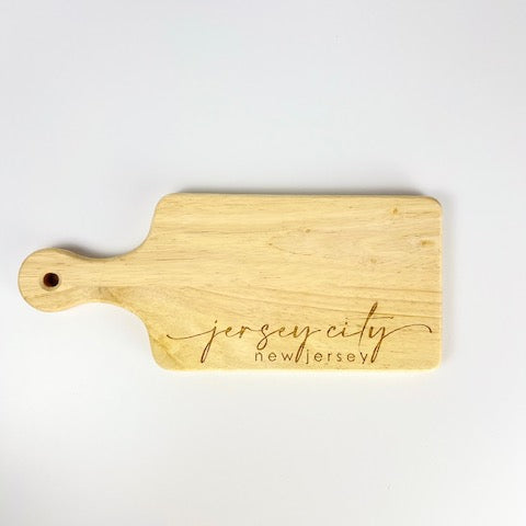 Wooden cutting board with 'Jersey City, New Jersey' engraving on a white background