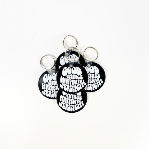Four circular keychains with text on a white background