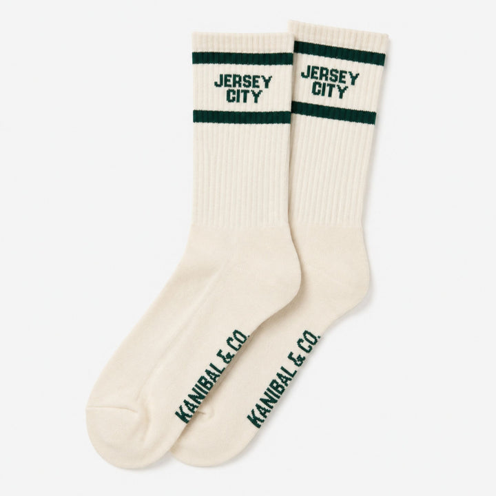 Pair of cream socks with green stripes and text on a white background