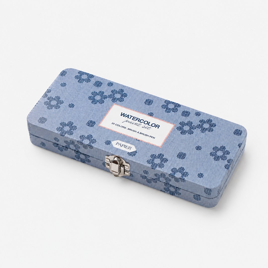 A rectangular metal watercolor pencil case with a blue floral pattern, featuring a silver clasp and a white label that reads 'WATERCOLOR PENCIL SET' and 'PAPIR'.