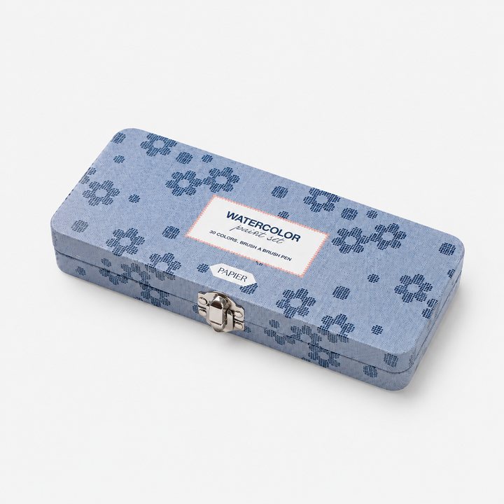 A rectangular metal watercolor pencil case with a blue floral pattern, featuring a silver clasp and a white label that reads 'WATERCOLOR PENCIL SET' and 'PAPIR'.