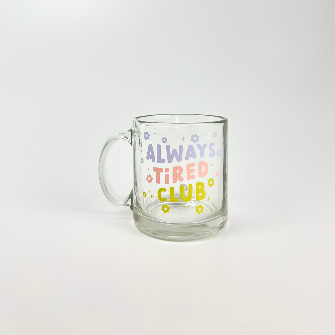 Talking Out of Turn always tired mug clear glass with pastel ALWAYS TIRED CLUB text and small flower accents