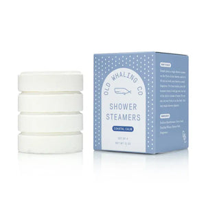 4 shower steamer tablets stacked up next to rectangular packaging 