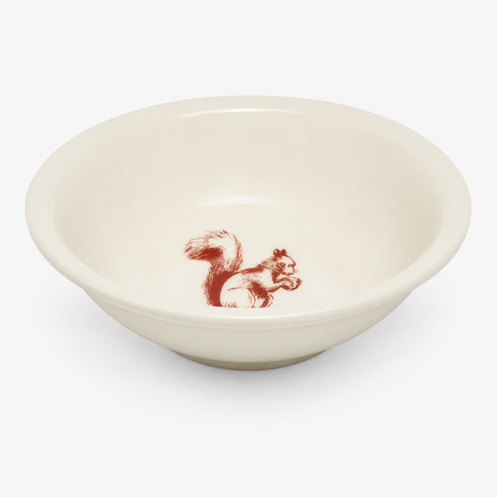 An off-white ceramic bowl featuring a small red sketch-style illustration of a squirrel inside the bottom center, set against a plain light gray background.