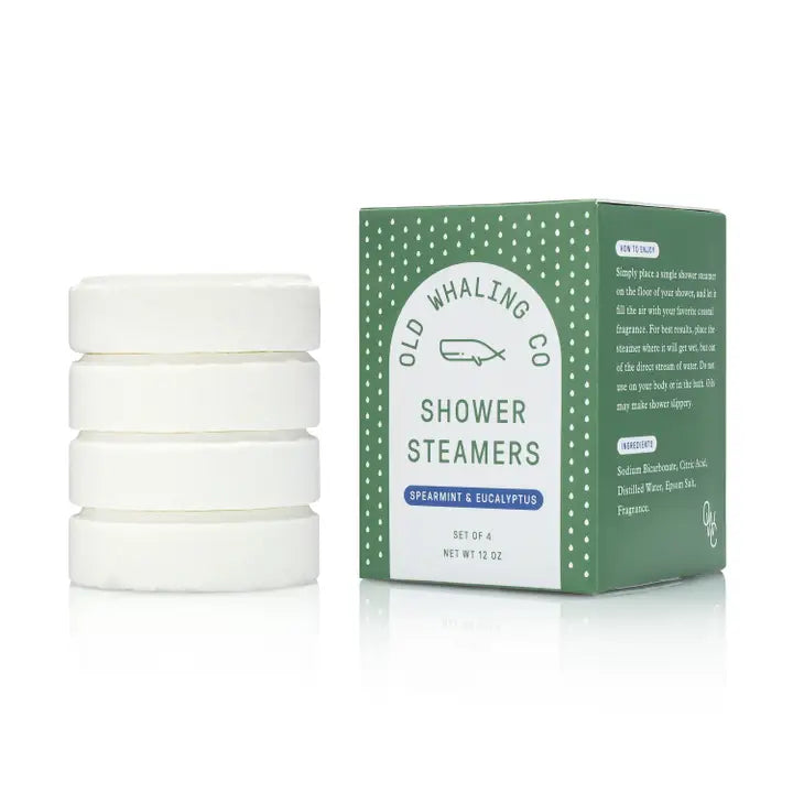 4 shower steamer tablets stacked up next to rectangular packaging 
