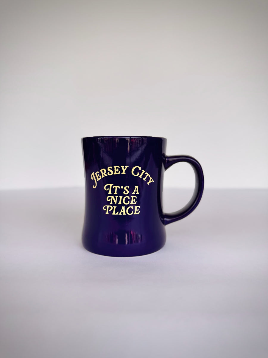 Kanibal Co. Jersey City mug in dark purple with yellow text saying Its a nice place
