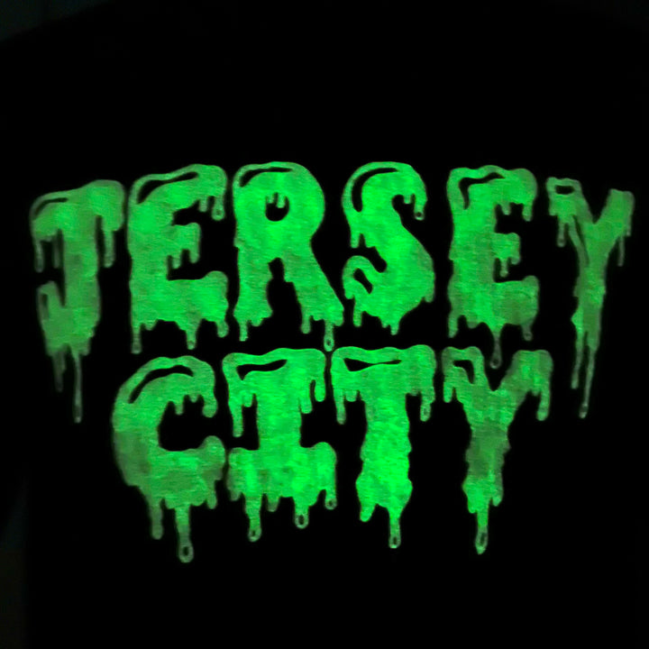 Close-up of black Kanibal & Co Jersey City slime tee with glowing green dripping letters
