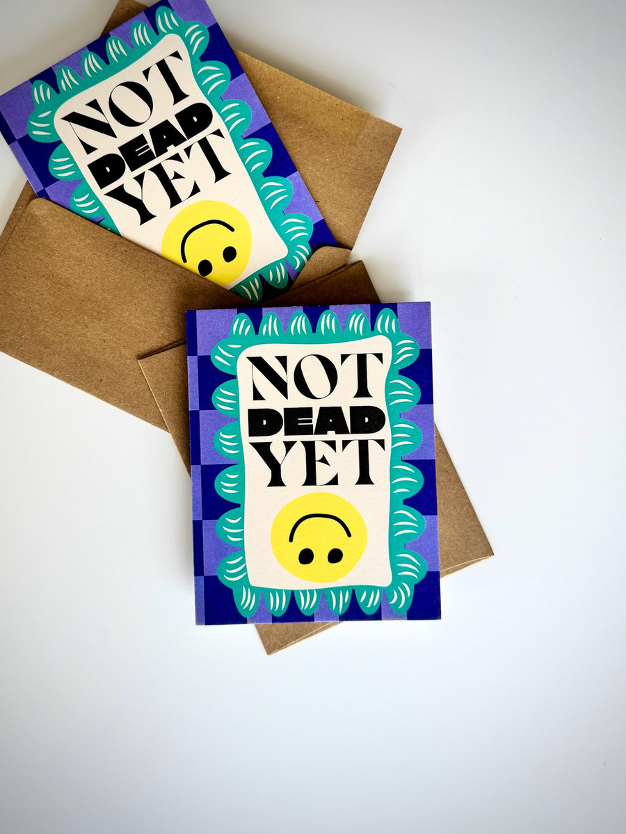 JamSauce Not Dead Yet birthday card with bold typography and smiley face design on blue patterned background