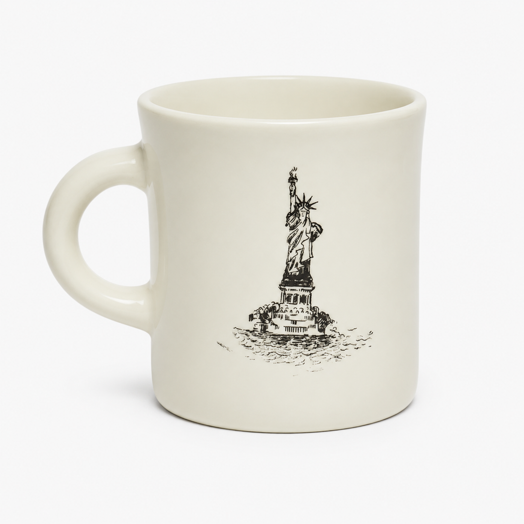 An off-white ceramic coffee mug featuring a black line art illustration of the Statue of Liberty on a plain white background.