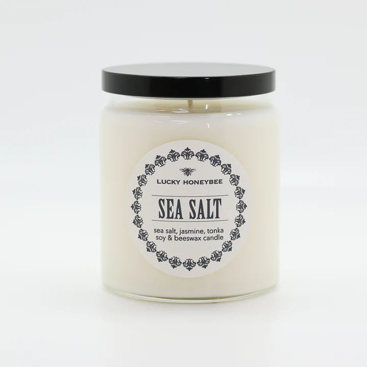 The Lucky Honeybee sea salt candle in a clear glass jar with black lid featuring soy and beeswax blend