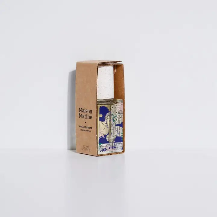 Maison Matine Hasard Bazar perfume bottle in cardboard box with blue beige label and speckled white cap on white background