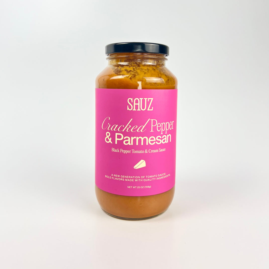 Sauz jar of cracked pepper parmesan pasta sauce in a clear glass jar with bright pink label and black lid