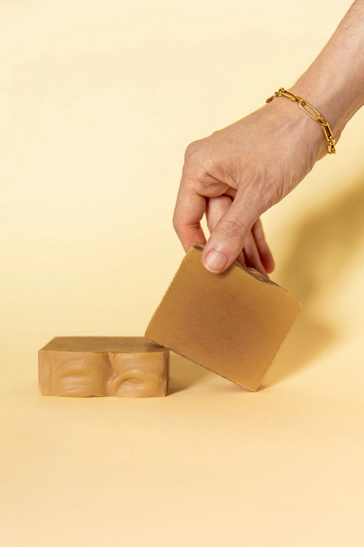 Hand holding Slow North coconut oatmeal bar soap on a light background.