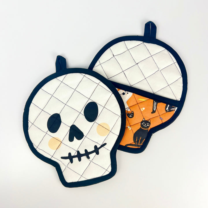 Danica skull pot holder set of two quilted skull shaped potholders white face orange cat print back