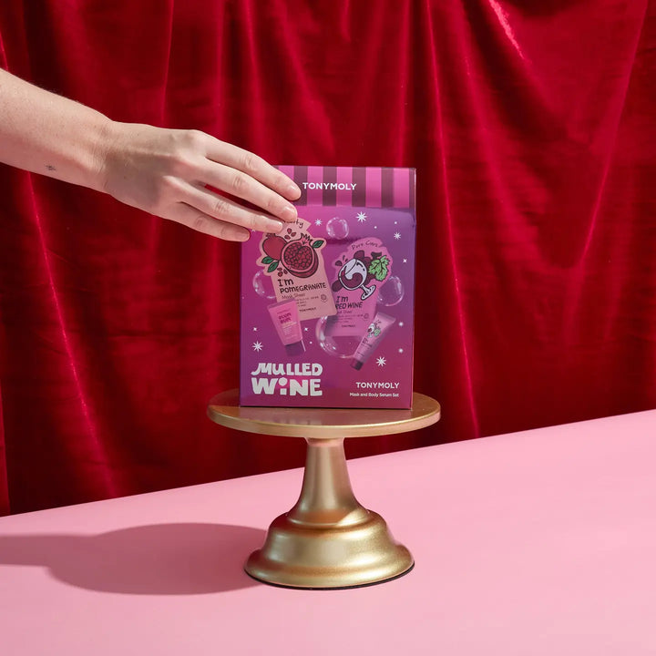 TonyMoly Mulled Wine Face and Body Set displayed on a golden pedestal with a hand reaching for it