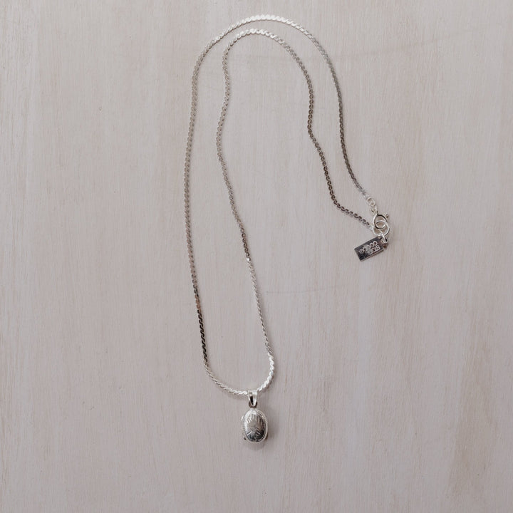 A small oval shaped sterling silver locket on a silver chain