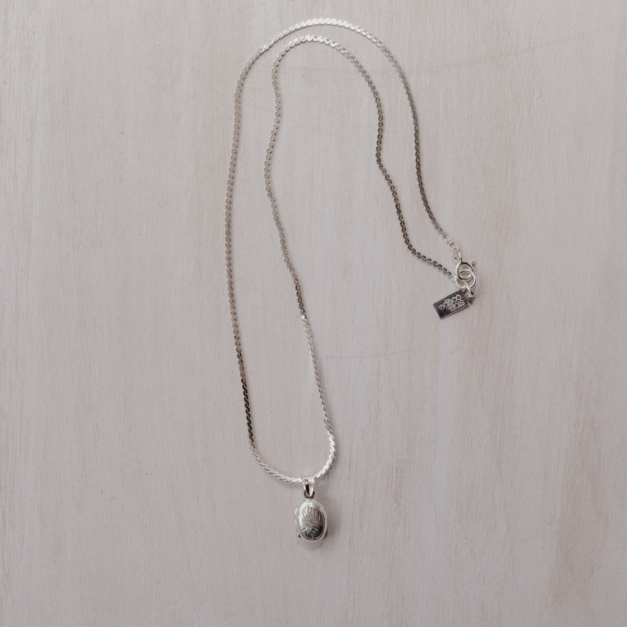A small oval shaped sterling silver locket on a silver chain