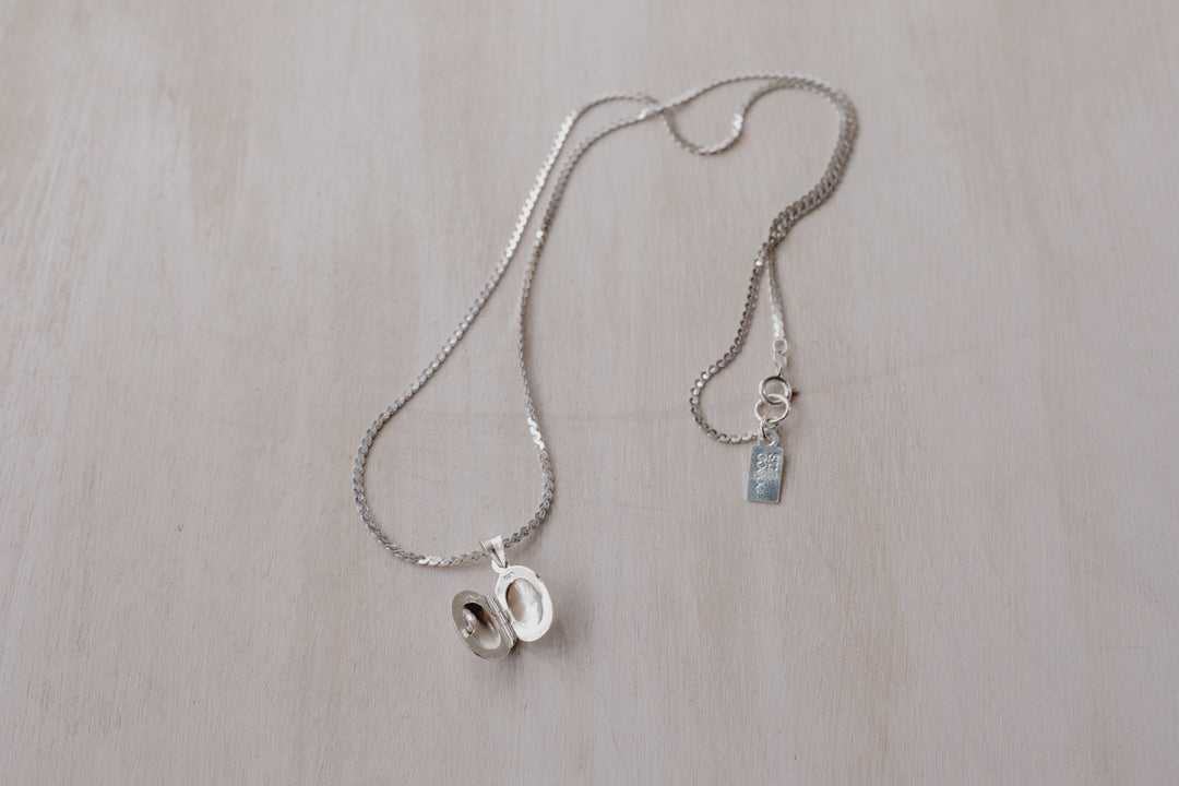 silver chain with an opened silver oval shaped locket