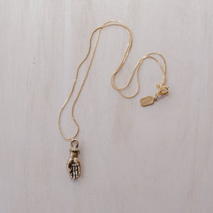 A bronze figa hand charm on a gold chain