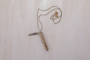 An opened masonic knife pendant paired with an antique brass chain