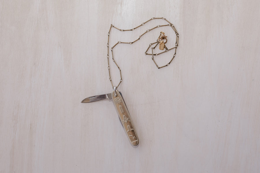 An opened masonic knife pendant paired with an antique brass chain