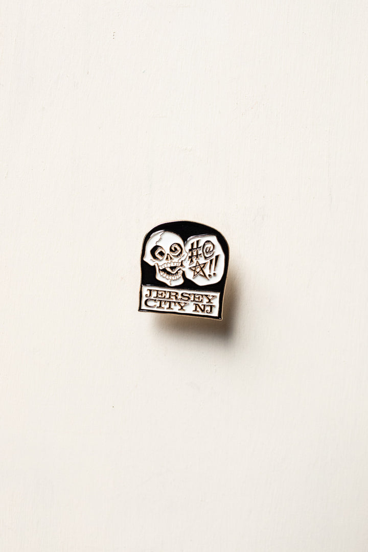 black and white pin with skull on headstone 