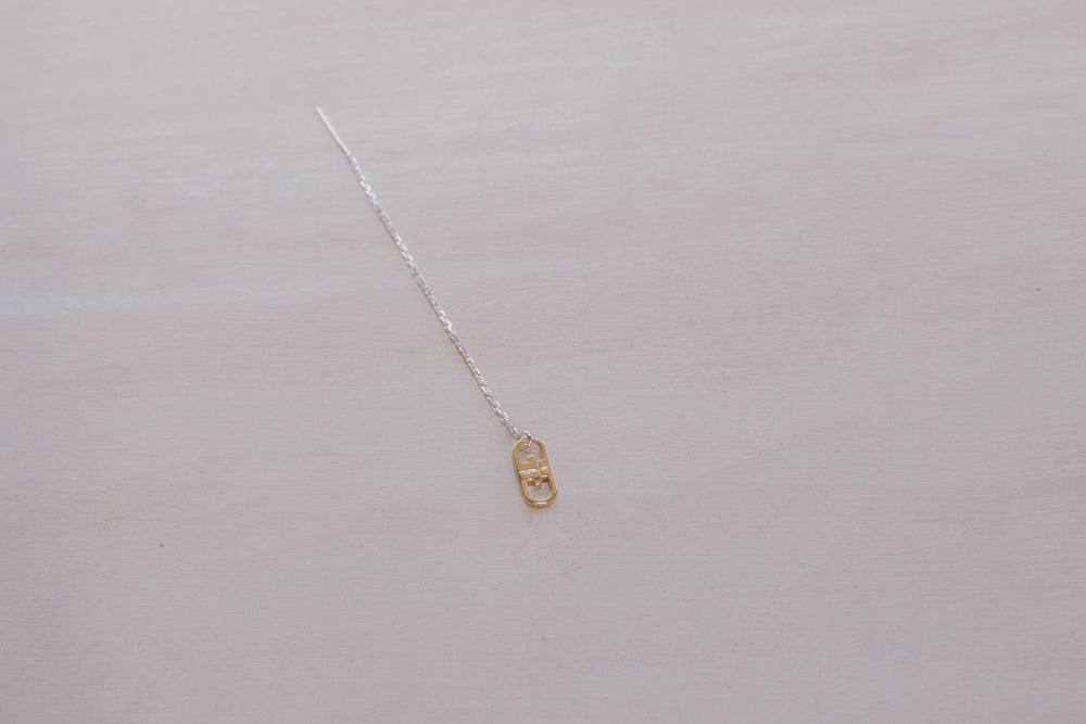 single earring with silver chain and gold charm