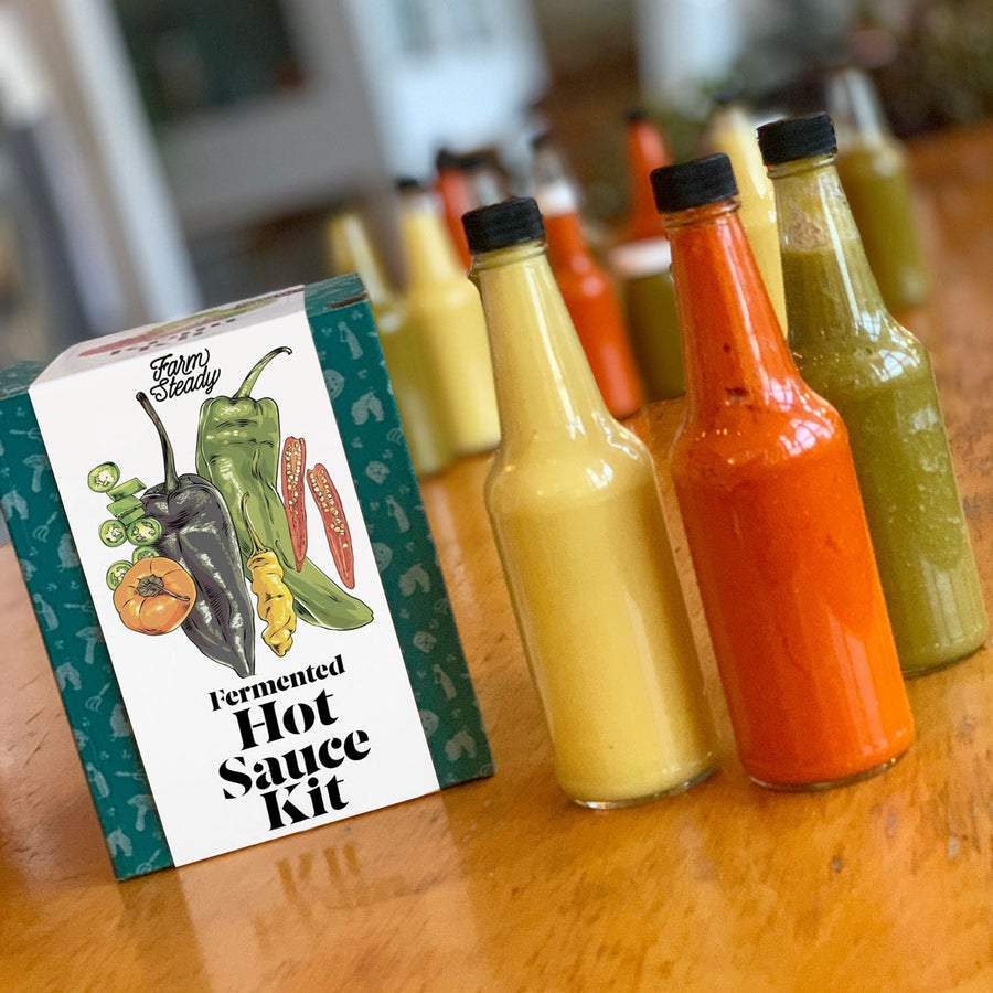 green and white box of product next to multiple bottles of hot sauce.