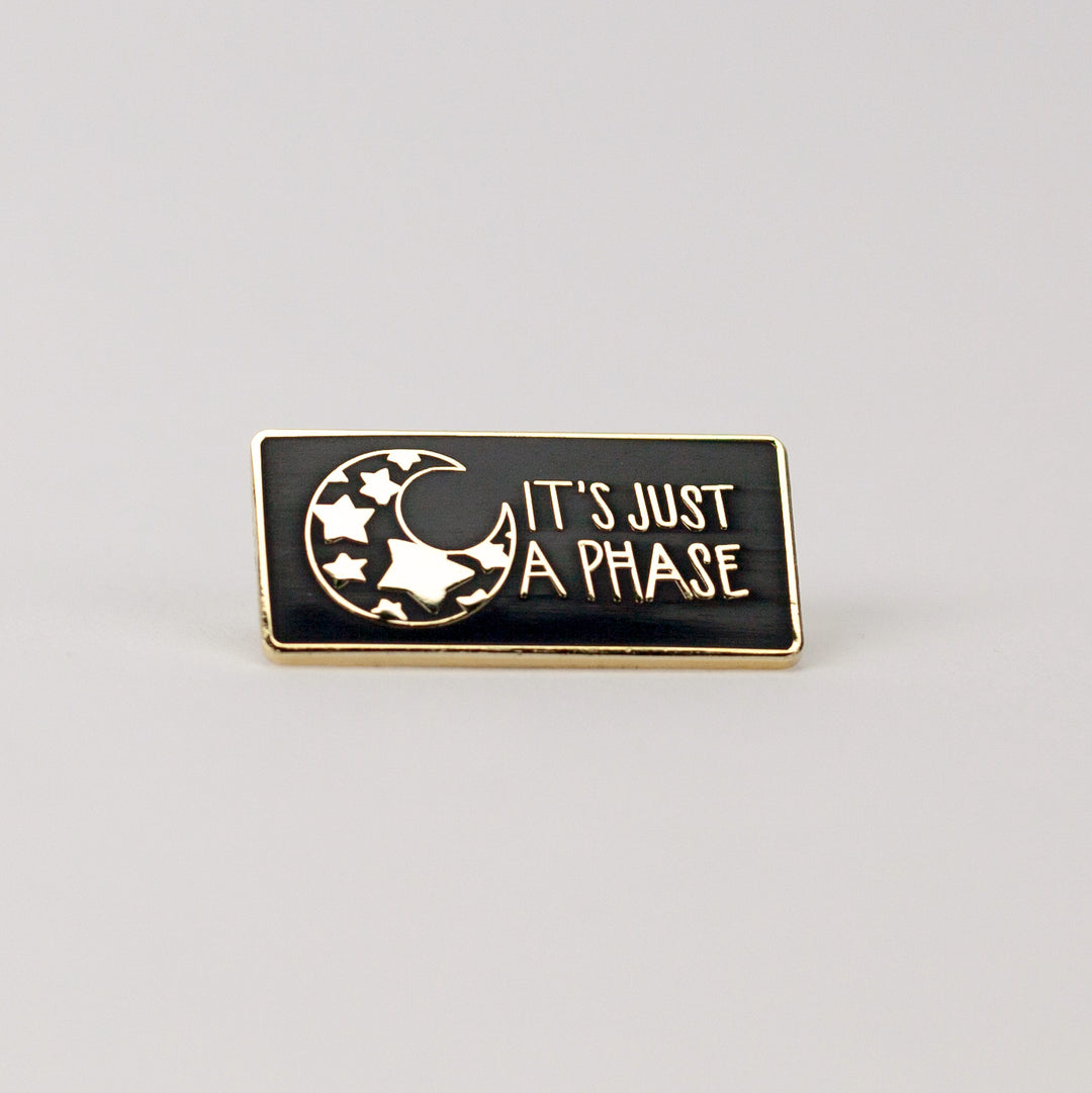 black and gold rectangle pin with illustration of mood with stars inside it.