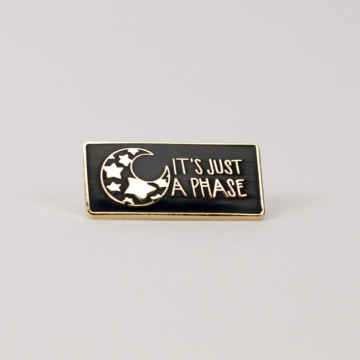 black and gold rectangle pin with illustration of mood with stars inside it.