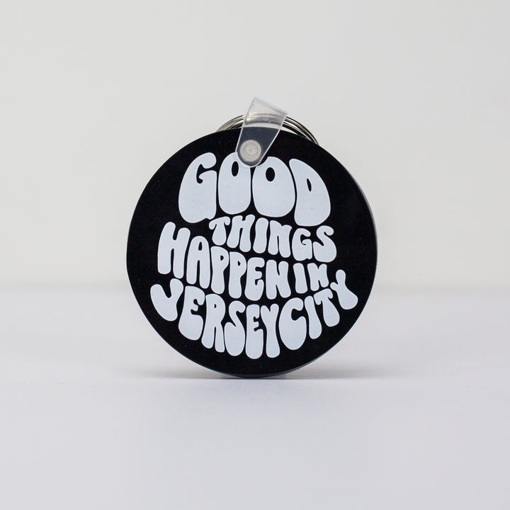 A black round key chain that reads "Good Things Happen in Jersey City"