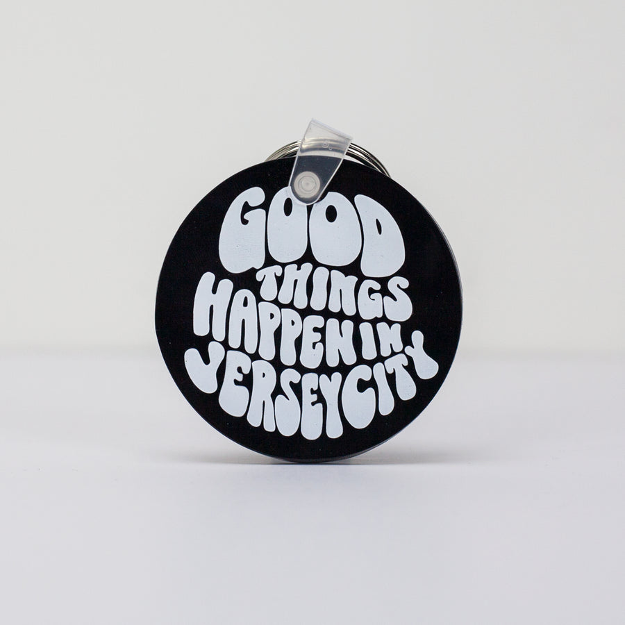 A black round key chain that reads "Good Things Happen in Jersey City"