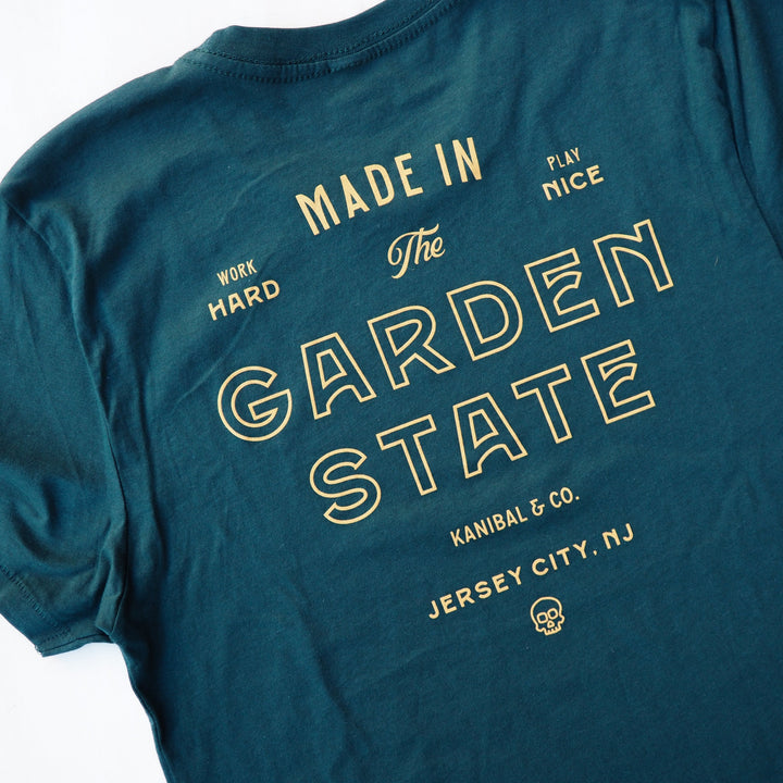 That back of a forest green tee shirt that reads "Made in The Garden State. Work Hard, Play Nice. Kanibal & Co. Jersey City, NJ" 