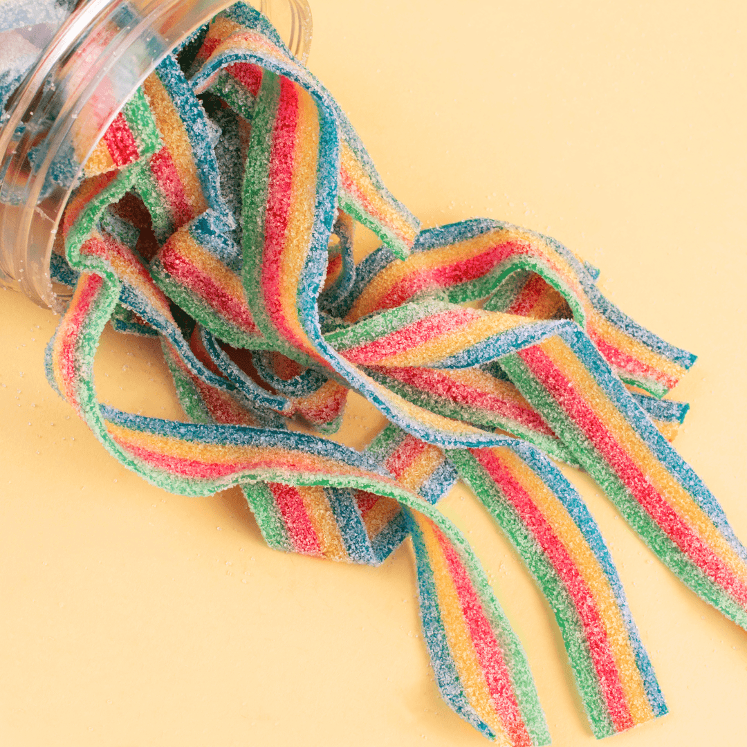 Rainbow sour belts spilling out of candy jar