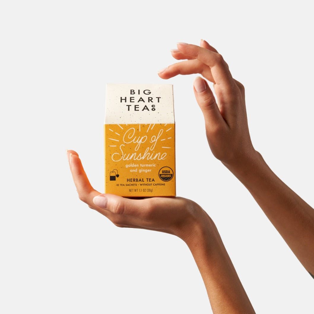 Big Heart Tea Co. herbal turmeric ginger tea Cup of Sunshine package held by hands