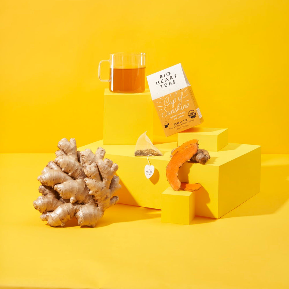Big Heart Tea Co herbal turmeric ginger tea with fresh ginger root, turmeric, tea bag, and brewed tea cup