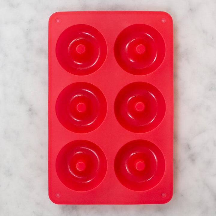 Red rectangular silicon baking tray with 6 round holes for donut mix