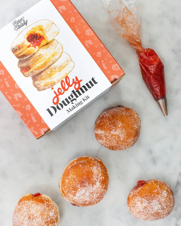 DIY jelly doughnut kit by Farm Steady with doughnuts and piping bag filled with jelly on marble surface