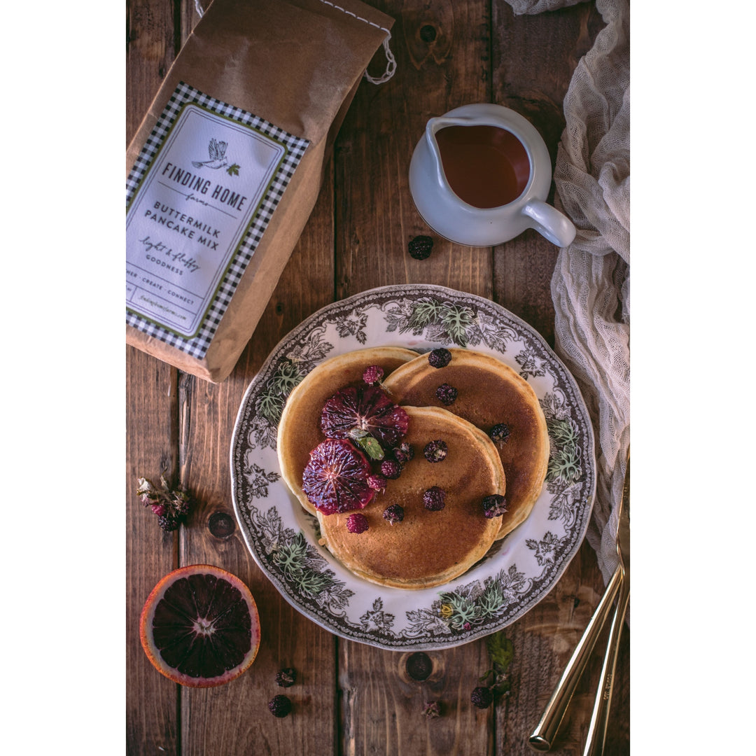 Finding Home Farms buttermilk pancake and waffle mix with pancakes topped with fruits on a decorative plate