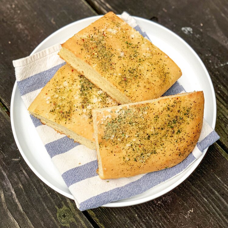 Garlic herb focaccia baking kit bread slices on white plate with blue striped napkin