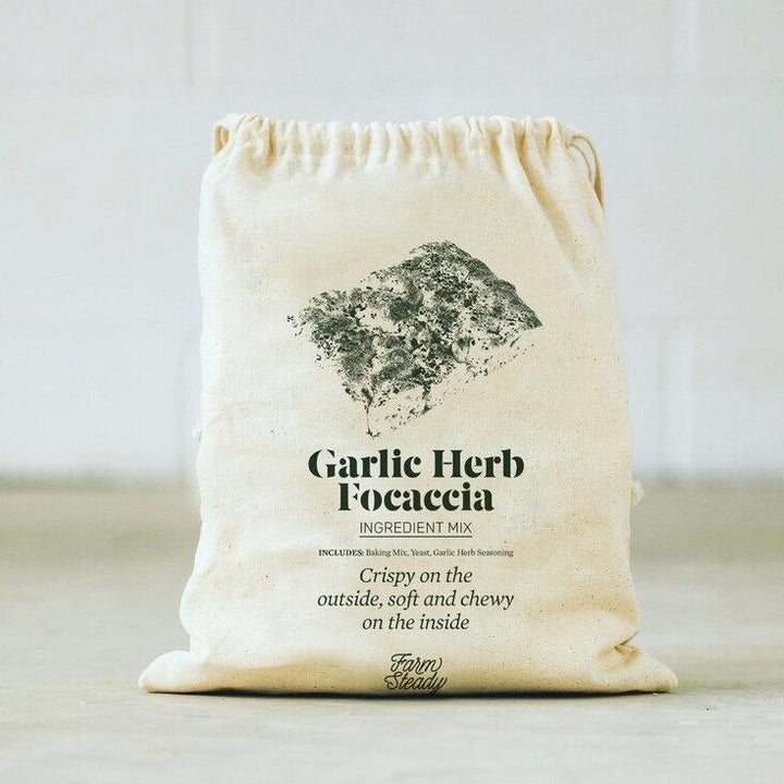 Farm Steady garlic herb focaccia baking kit in a beige drawstring bag with ingredient mix and seasoning