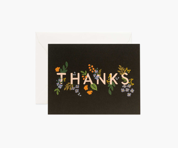 A rectangular card with a black background that read "Thanks" with floral design coming out of the letters.